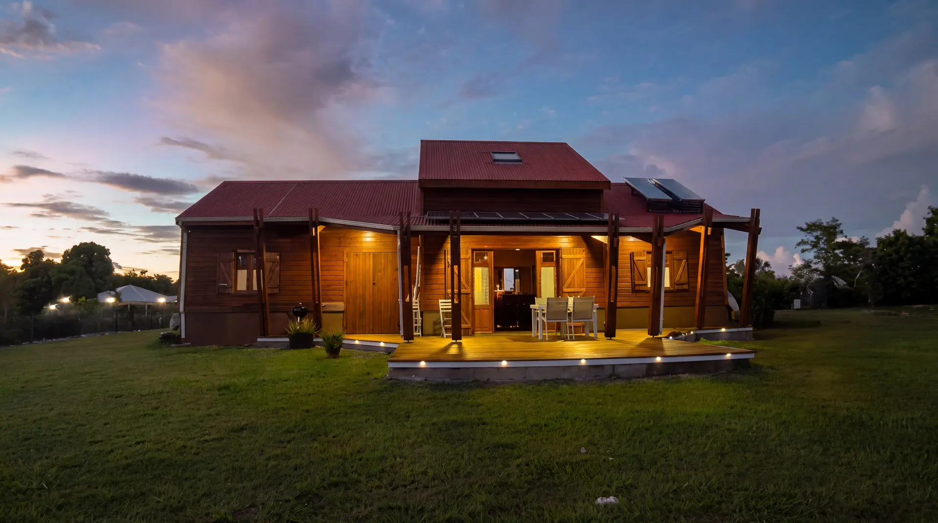 Maison en bois au crépuscule avec terrasse et panneaux solaires